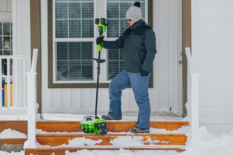Person using a snow removal tool on a set of snowy steps.