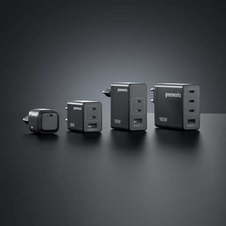 Four Greenworks power chargers of different sizes on a dark background